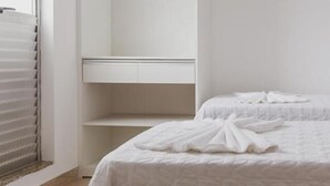 Un dormitorio con cama, armario y ventana con persianas.
