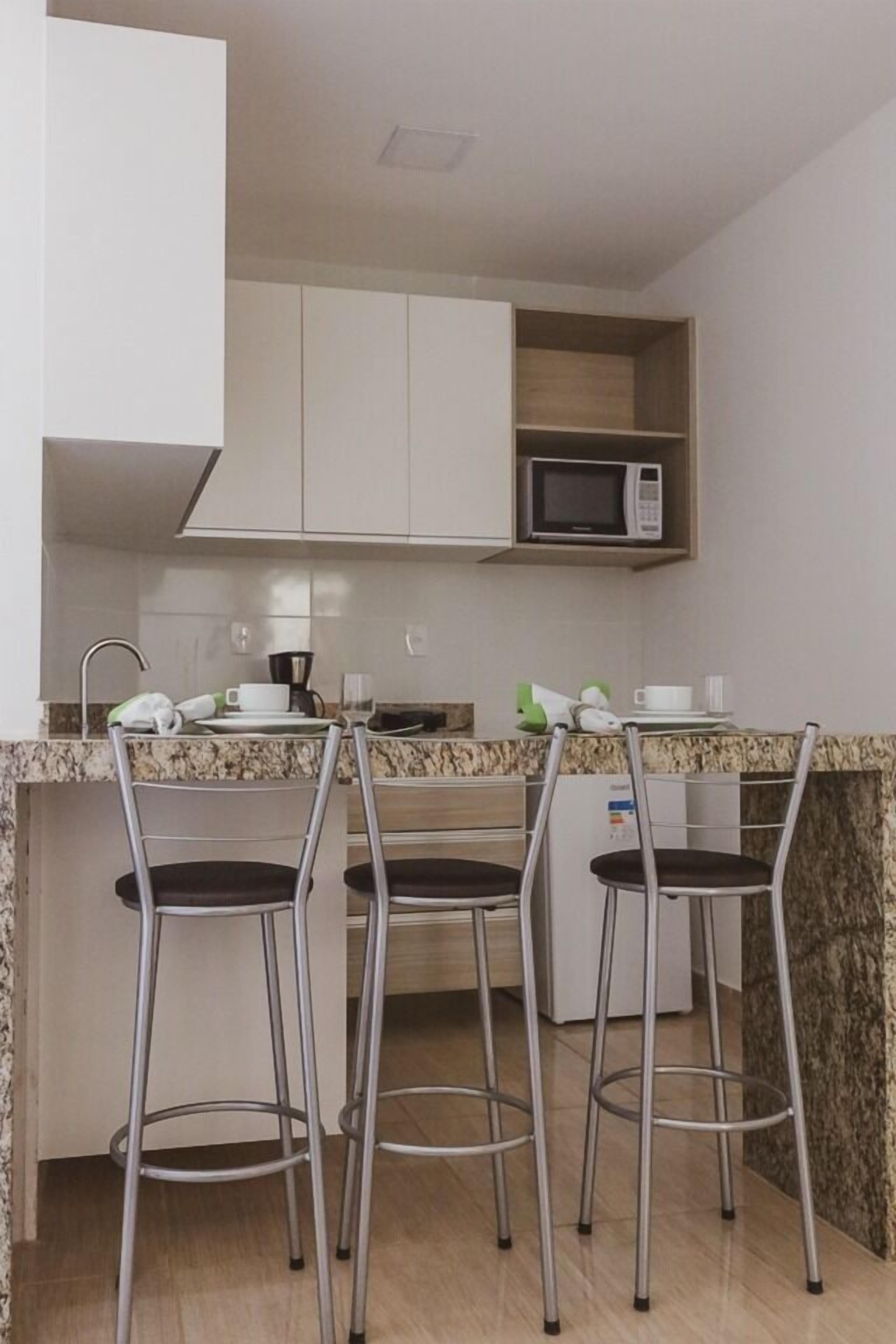 Una cocina moderna con tres taburetes de bar, un microondas y una cafetera.