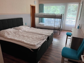 A room with a bunk bed, a desk, and a chair.