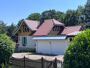 A two-story house with a red-tiled roof, a garage, and a fenced driveway. - Group house for up to 30 people in the Southern Harz Mountains - Group house for up to 30 people (Bad Sachsa)