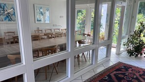 Un vaste espace dédié à la salle à manger, doté de murs en verre, de tables et de chaises en bois.