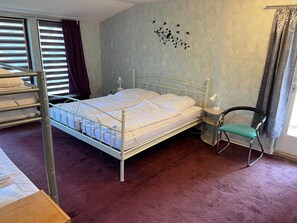 A bedroom with a bunk bed, a single bed, a chair, a nightstand, and a wall decoration. - Group house for up to 30 people in the Southern Harz Mountains - Group house for up to 30 people (Bad Sachsa)