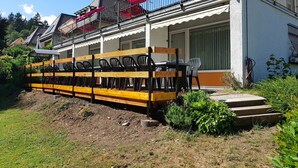 Un bâtiment doté d’un balcon, d’un espace extérieur aménagé pour s’asseoir et d’un jardin.