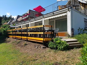 Een gebouw met een balkon, zitplaatsen buiten en een tuin.