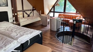 Une chambre à coucher comprenant un lit, une chaise, une petite table, un canapé et un escalier.