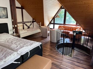 Een slaapkamer met een bed, een stoel, een klein tafeltje, een bank en een trap.