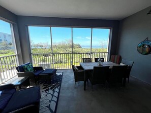 Un balcón con vistas al mar, una mesa de comedor con sillas y un sofá.