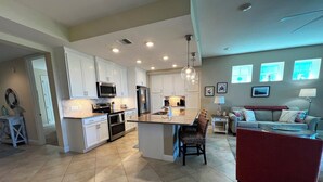 Una cocina moderna con armarios blancos, electrodomésticos de acero inoxidable y una isla central.