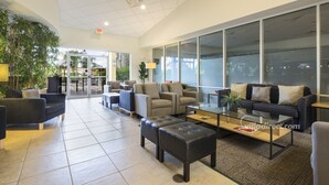 A spacious lobby with multiple seating areas, including sofas and armchairs, a coffee table, and a glass-top table. - Encantada Rose by VillaDirect (Kissimmee)