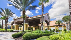 A hotel entrance with a covered patio, palm trees, and well-manicured landscaping. - Encantada Rose by VillaDirect (Kissimmee)