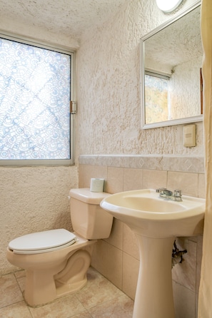 Bathroom features a pedestal sink, toilet, and mirror.