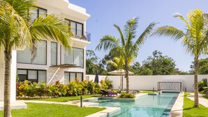A modern house with a swimming pool, surrounded by palm trees and a well-maintained lawn. - Neem Tulum (Tulum)