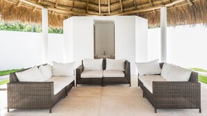 A covered outdoor seating area with wicker furniture and a thatched roof. - Neem Tulum (Tulum)