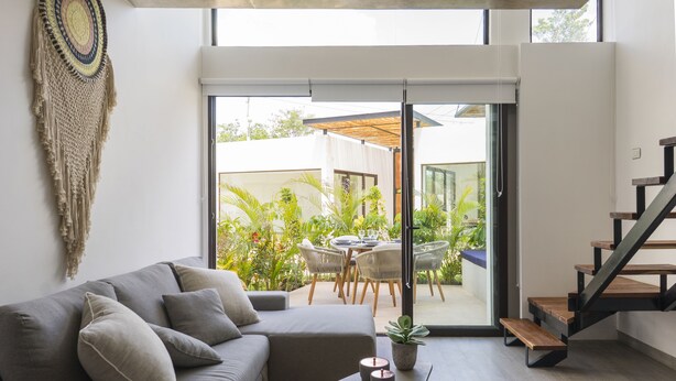 A modern living room with a grey sofa, a coffee table, and a staircase. - Neem Tulum (Tulum)