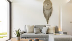 A modern living room with a grey sofa, a wooden coffee table, and a potted plant. - Neem Tulum (Tulum)