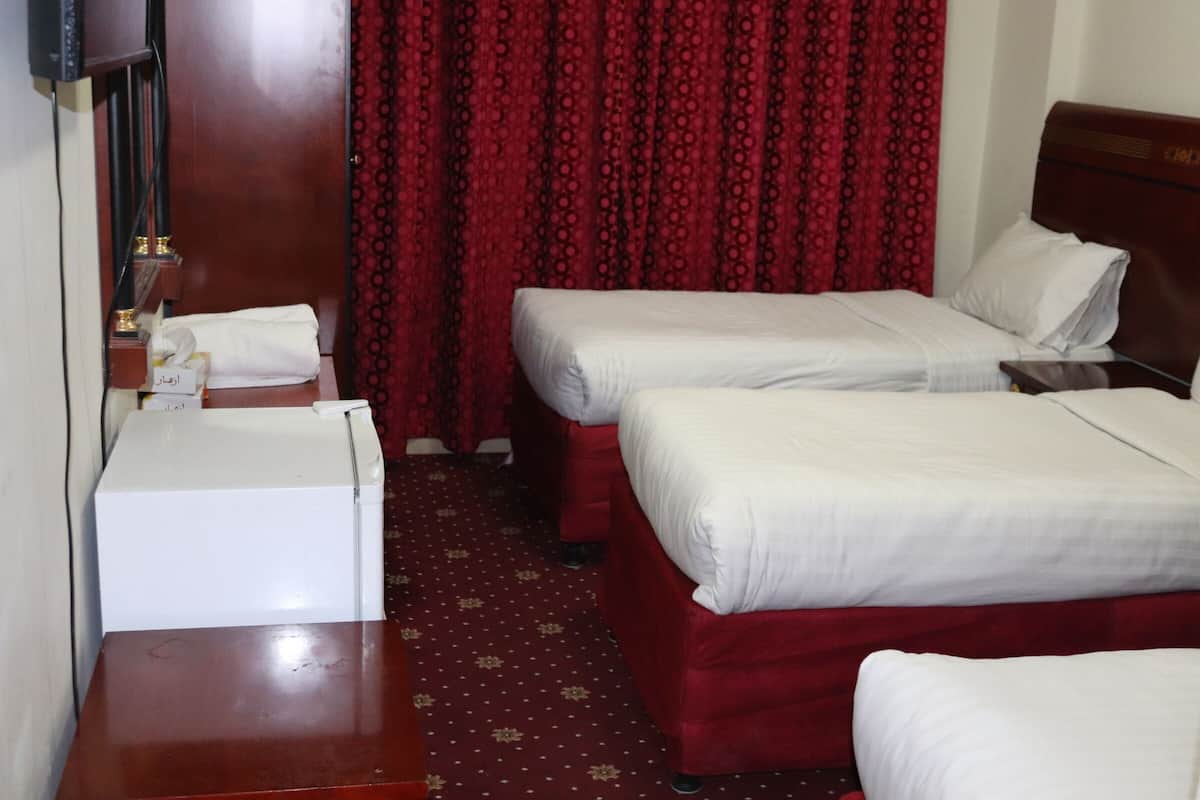 Une chambre d’hôtel avec deux lits, un bureau, une moquette rouge et un rideau rouge.