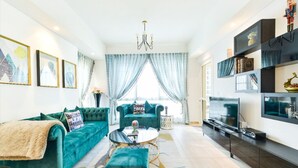 A modern living room with teal sofas, a coffee table, and a TV.