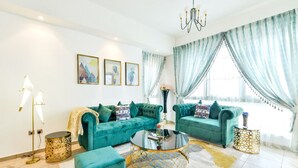 A living room with two teal sofas, a round coffee table, and a chandelier.