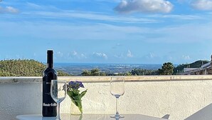 A bottle of Monte Etollo wine, a glass, and a vase with flowers on a table with a view of a landscape. - Cute house nearby Monchique - Algarve. Long term rental on request. (Casais)