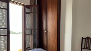 A room with a bed, a wooden door, and a chair. - Cute house nearby Monchique - Algarve. Long term rental on request. (Casais)