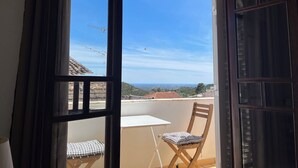 Ein Balkon mit Tisch und Stuhl, Blick zum Himmel und eine entfernte Landschaft.