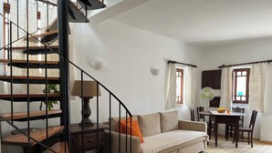 A living room with a staircase, a sofa, a dining table, and chairs. - Cute house nearby Monchique - Algarve. Long term rental on request. (Casais)