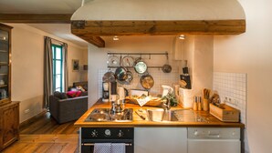 Una cocina con vigas de madera, un rincón de comedor con sofá y vistas al exterior.