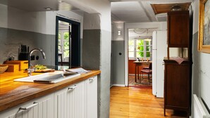A kitchen with a wooden countertop, white cabinets, and a view into the dining area.