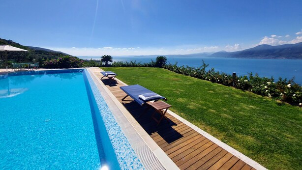 A swimming pool with lounge chairs and a view of a lake and mountains. - Lake Garda luxury studio with pool (Torri del Benaco)