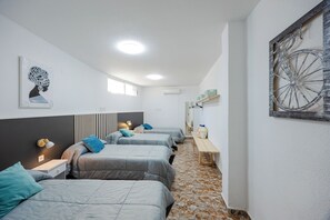 A hotel room with four beds aligned along the wall, a wooden bench, and a wall-mounted bicycle decoration. - Fidalsa Grand White House (Mutxamel / Muchamiel)