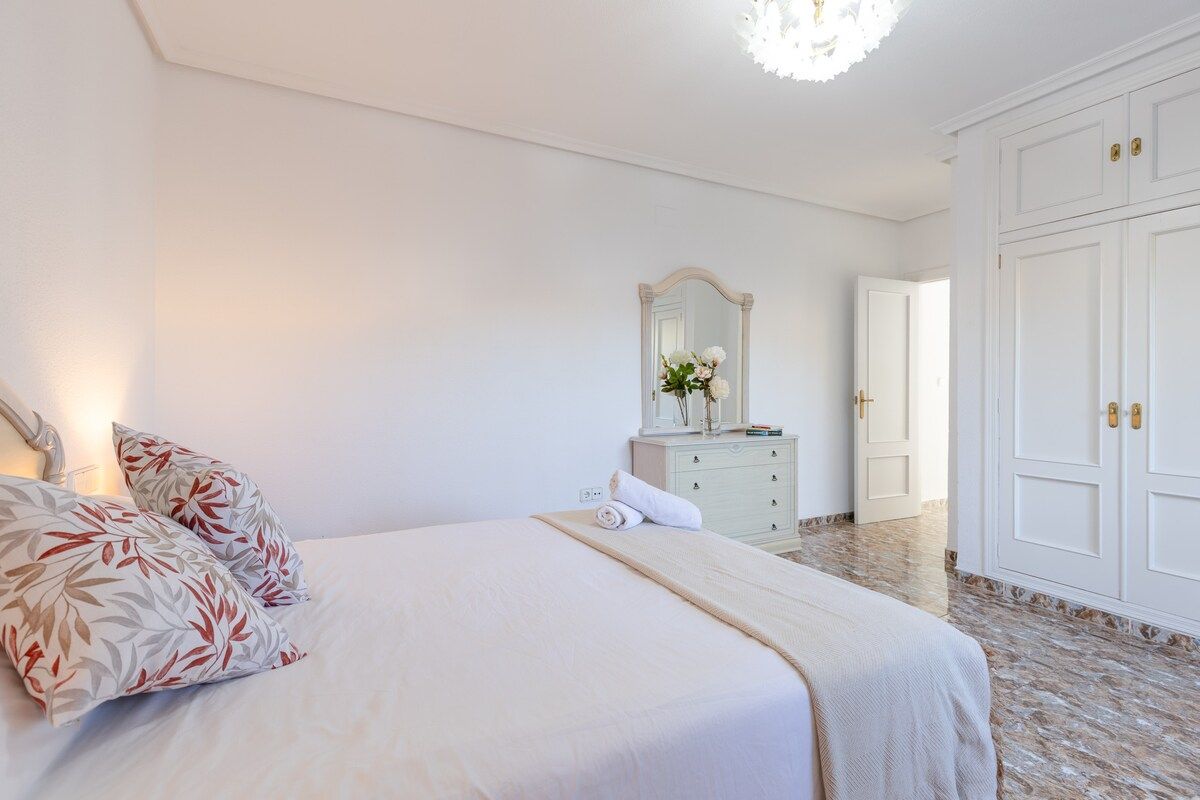 A bedroom with a bed, a dresser, a mirror, and a wardrobe.