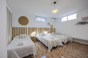 Une chambre d’hôtel avec deux lits, une décoration murale ronde en fibres tressées, un luminaire au plafond et une fenêtre.