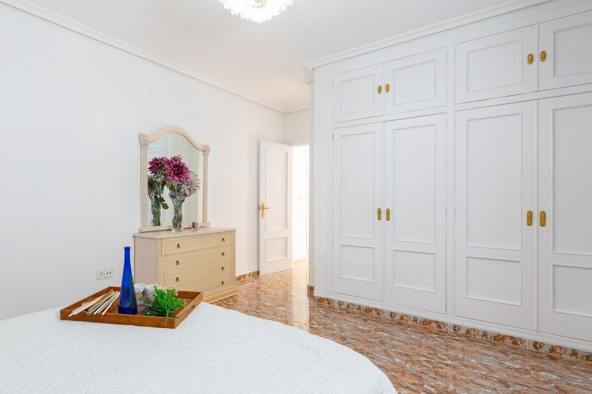 Une chambre à coucher avec un lit, une commode, un miroir et une armoire.