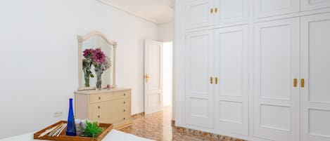 A bedroom with a bed, a dresser, a mirror, and a wardrobe.