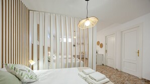 A hotel room with a bed, a nightstand, a lamp, a mirror, and a door. - Fidalsa Grand White House (Mutxamel / Muchamiel)