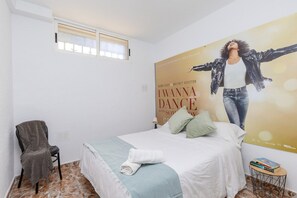 A bedroom with a bed, a chair, a small table, and a poster on the wall. - Fidalsa Grand White House (Mutxamel / Muchamiel)