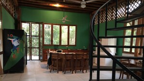 Cozinha com bancada de madeira, um laptop e área de refeições com cadeiras.