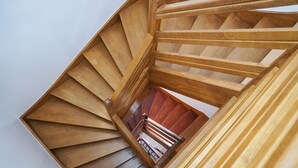 A wooden spiral staircase with a view of a red railing and a white wall. - La Maison Charentonneau (Maisons-Alfort)