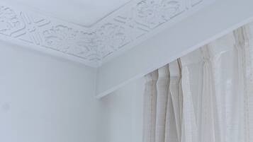 Esquina de una habitación con paredes y techo blancos, con molduras decorativas.