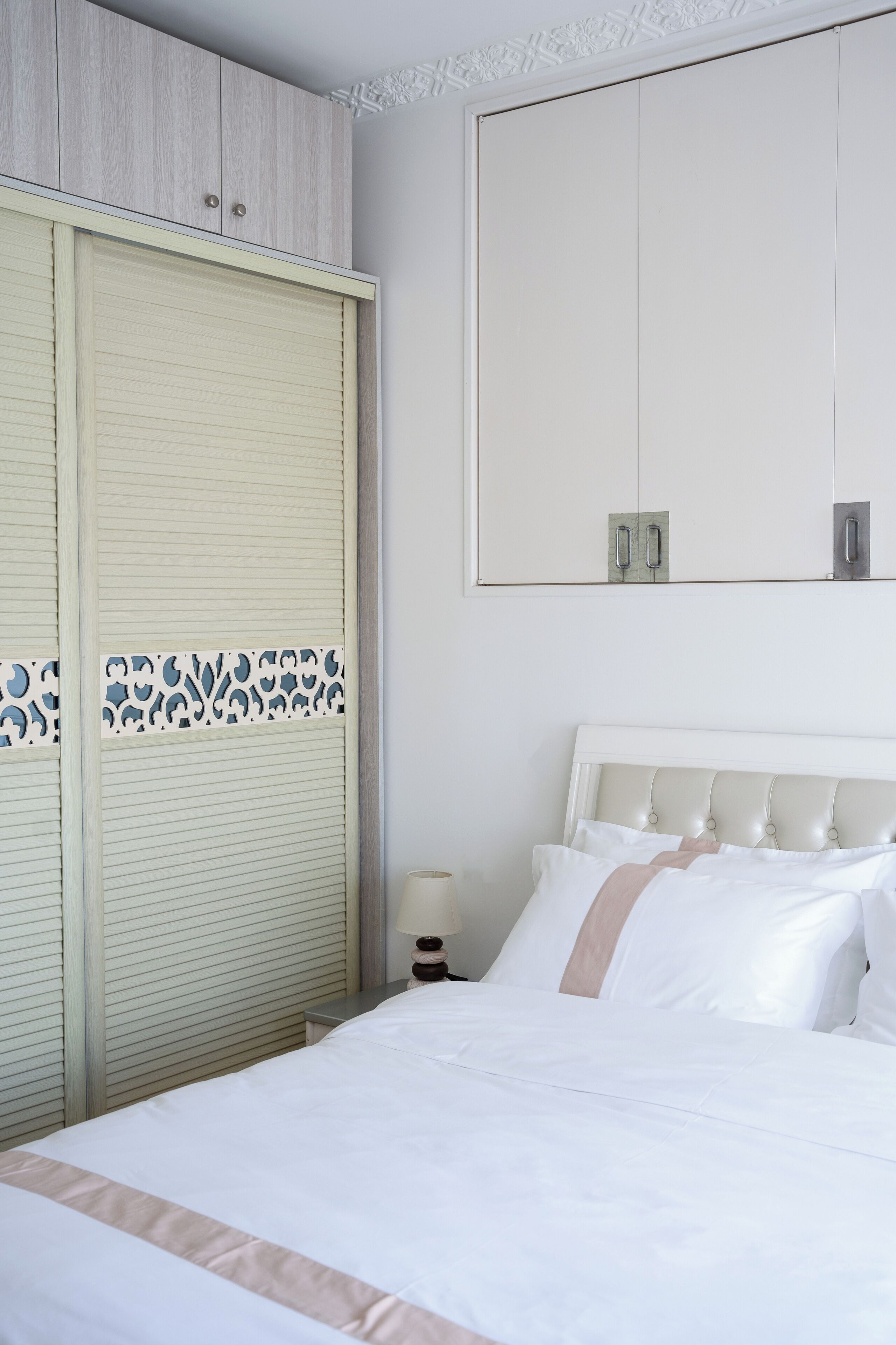 A neatly arranged bedroom with a bed, a wardrobe, and a nightstand.