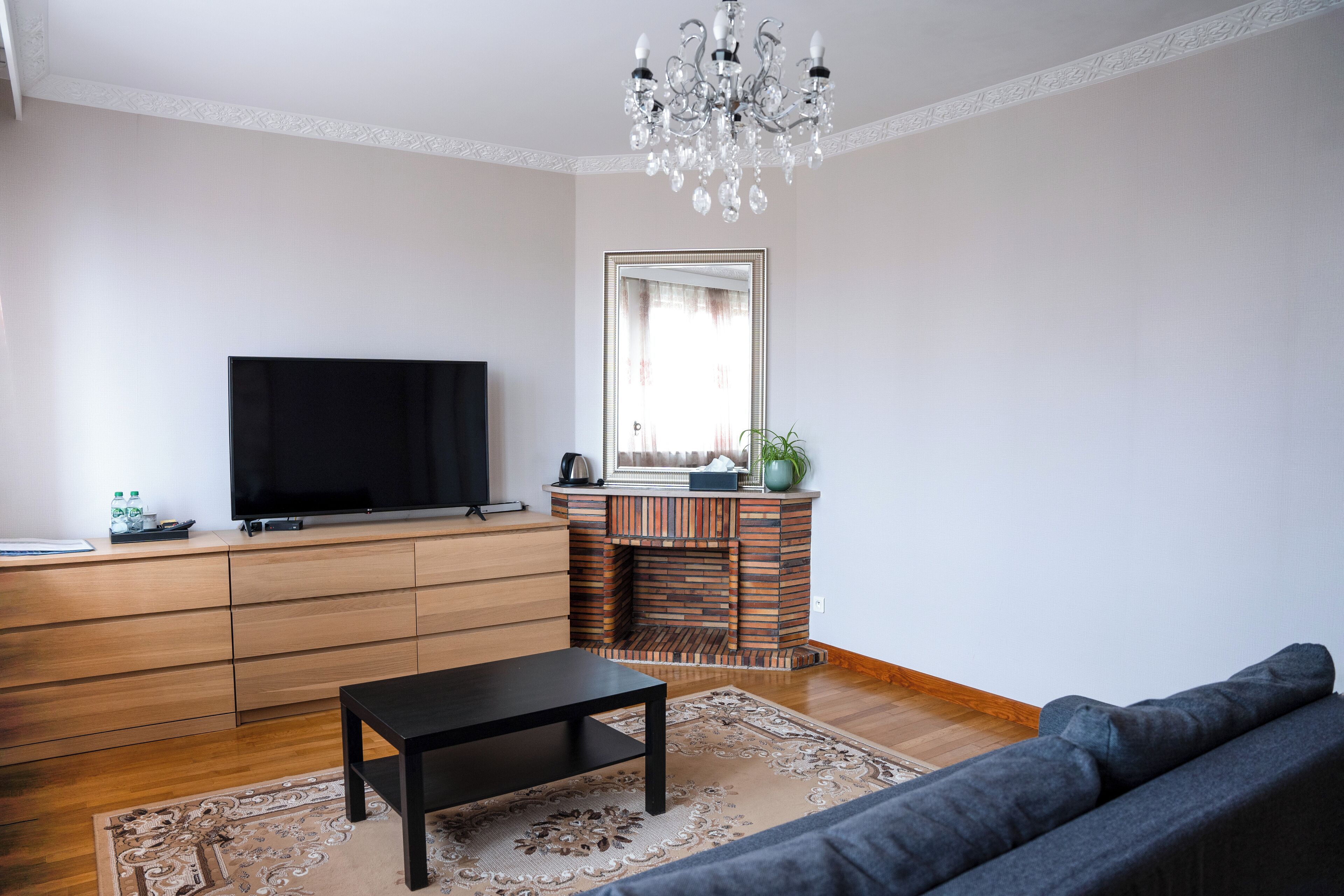 Una sala de estar con televisión de pantalla plana, chimenea, sofá y candelabro.