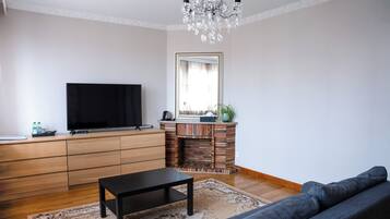 Una sala de estar con televisión de pantalla plana, chimenea, sofá y candelabro.