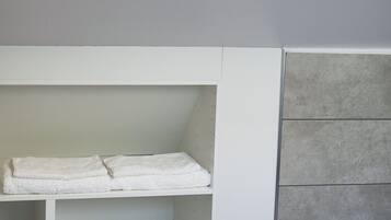 Una habitación con tragaluz, un banco empotrado blanco con estantes y paredes de baldosas grises.