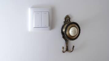 A white wall with a white switch and a decorative metal hook.