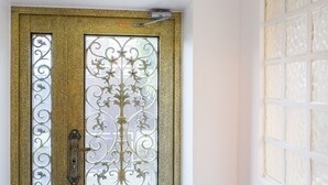 A door with intricate metalwork and a decorative glass panel. - La Maison Charentonneau (Maisons-Alfort)