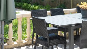 An outdoor patio with a table and chairs, a green umbrella, and a wooden fence in the background. - La Maison Charentonneau (Maisons-Alfort)