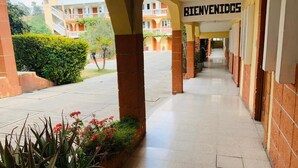 A covered walkway with a sign reading "BIENVENIDOS" leading to a building with multiple balconies. - Hotel Real Classic Inn (Salcajá)