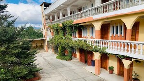 A building with multiple balconies, a covered walkway, and potted plants. - Hotel Real Classic Inn (Salcajá)