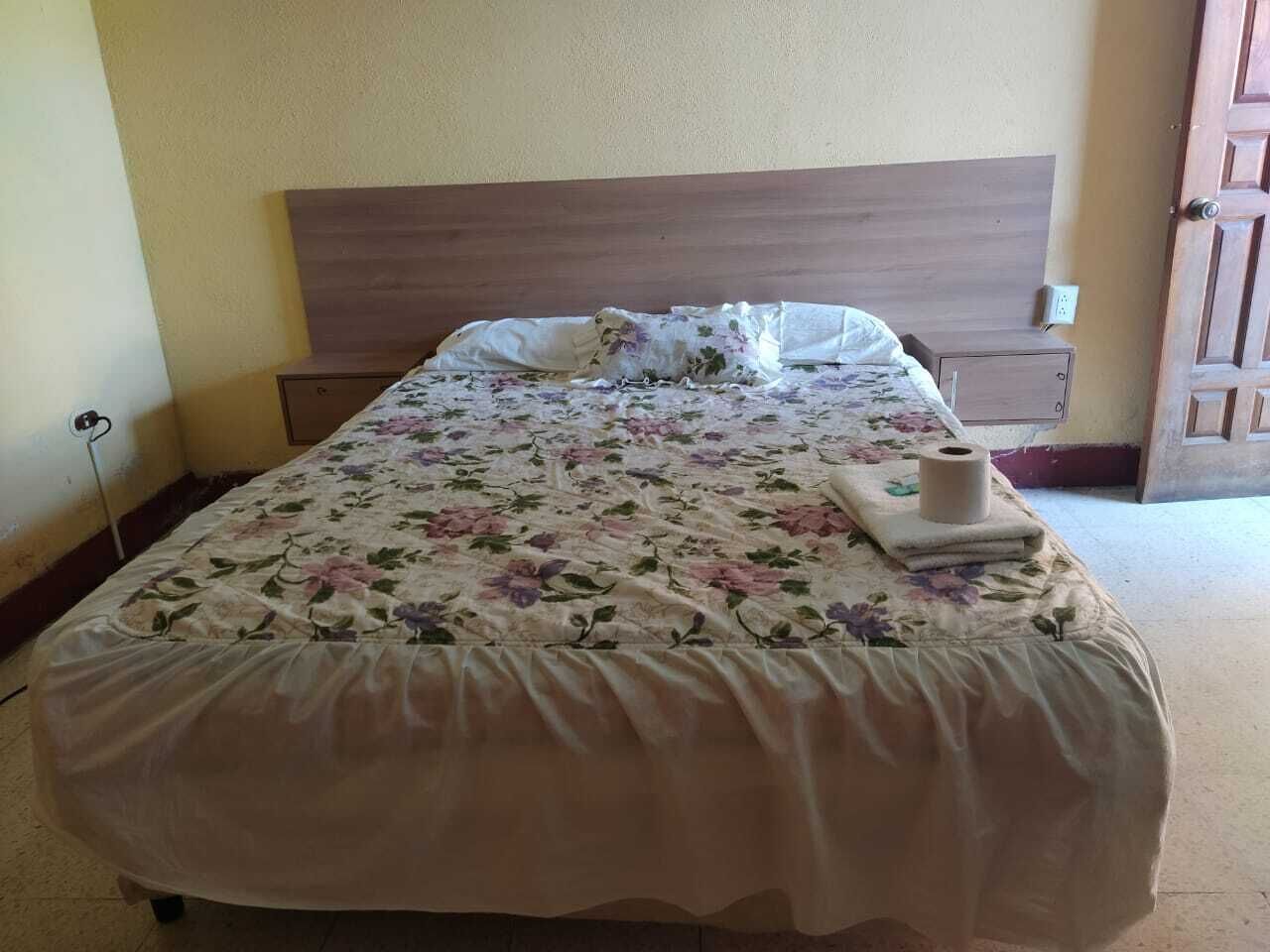 Una cama bien hecha con un edredón floral y un cabecero de madera.