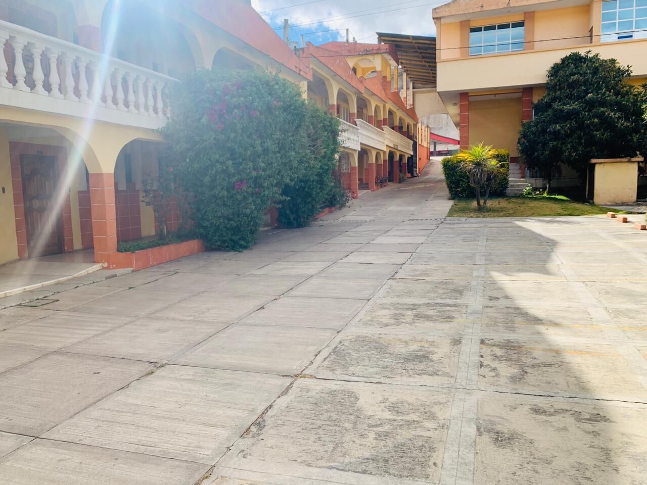 A courtyard with a tiled floor, surrounded by buildings with balconies and a covered walkway.